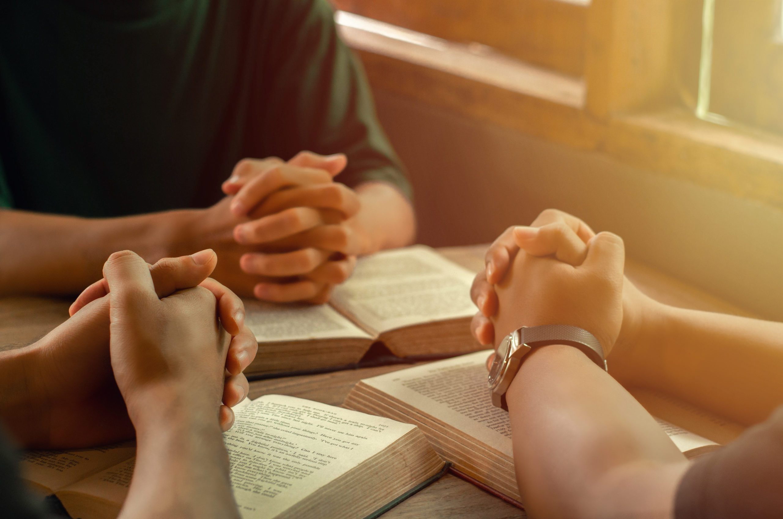 A group of young people holding hands in prayer according to God's faith in Christianity